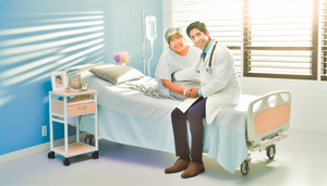 Un médico hispano de mediana edad, con expresión amable, sostiene la mano de una paciente anciana en una habitación de hospital iluminada naturalmente. La escena refleja empatía y conexión humana, destacando la importancia de la calidad de vida en el cuidado paliativo.